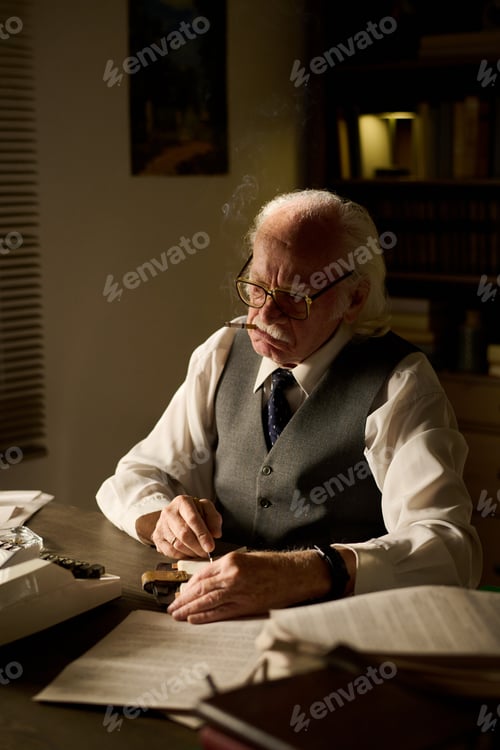 Preview: Senior Caucasian Man Writing Documents While Sitting at Desk in Office