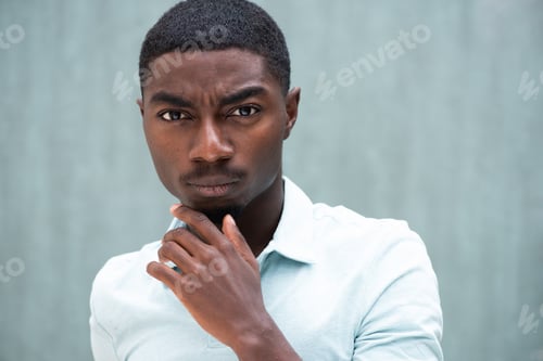Preview: Close up serious African American young man staring with hand to chin