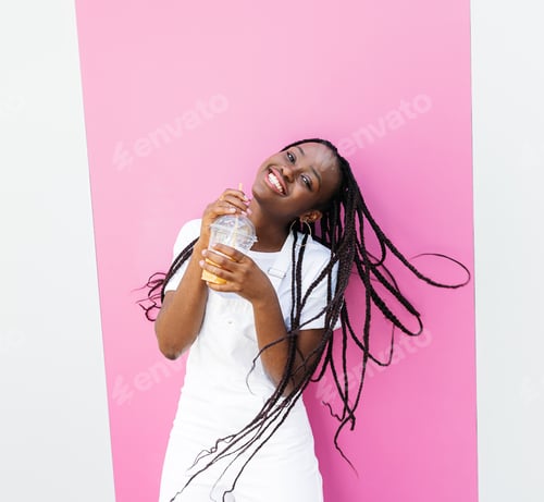 Preview: Happy girl with juice standing at the pink stripe and looking at camera
