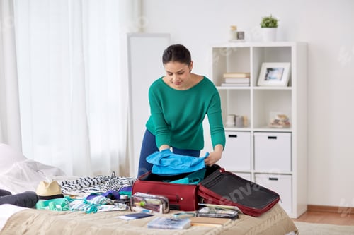 Preview: woman packing travel bag at home or hotel room