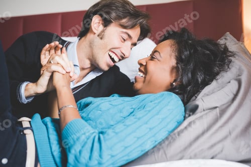 Preview: Multiethnic happy couple having fun laughing lying bed