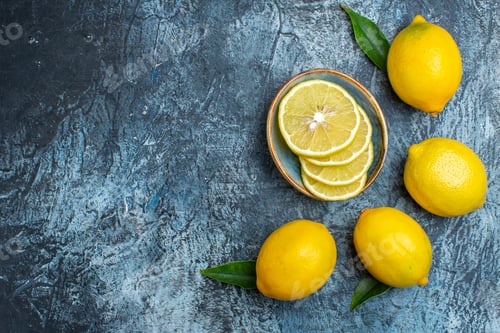 Preview: Top view of whole and cut fresh lemons with leaves on the left side on dark background