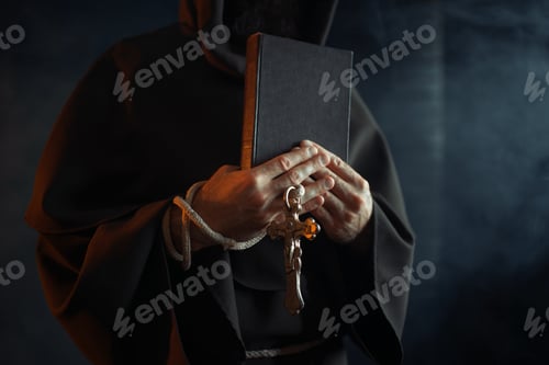 Preview: Medieval monk holds book and wooden cross in hands