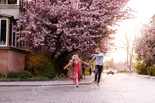 Preview: Stylish couple in the park with Sakura tree with blooming pink flowers. beautiful young couple, man