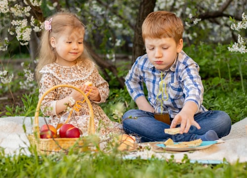 Preview: Two cheerful cute children on a picnic in nature among flowering trees in spring