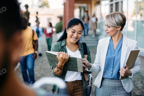 Preview: University teacher talking to her Asian female student at campus.