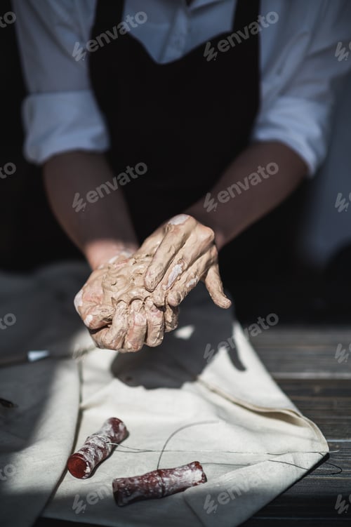 Preview: Woman's hands wet and dirty after working with clay in a pottery studio