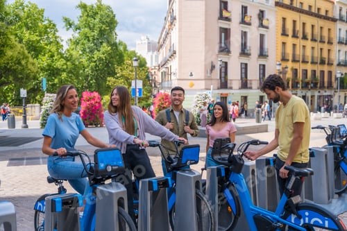 Preview: Group portrait of multi ethnic friends in the city next to rental bikes having fun