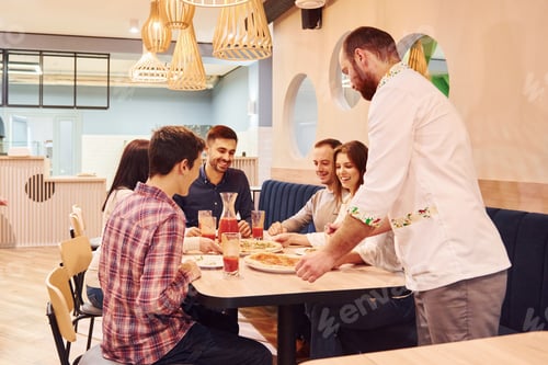 Preview: Chef delivers food. Group of young friends that sitting together indoors and eating pizza