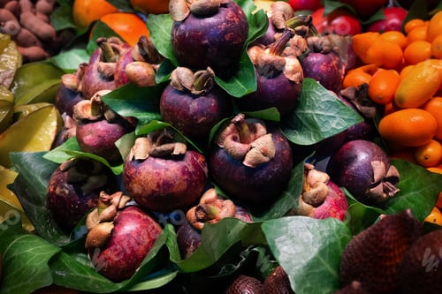 Preview: Mangosteens with their purple shells, showcased at a tropical fruit market.