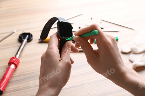 Preview: Technician fixing broken smart watch at table, closeup. Repair service