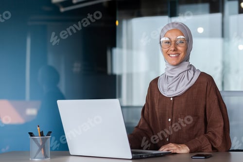 Preview: Portrait of successful businesswoman inside office with laptop, woman in hijab smiling and looking