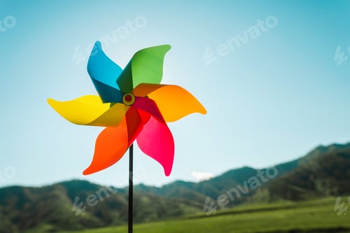 Preview: Multi-colored children's windmill, pinwheel in the background of green mountains and the sky