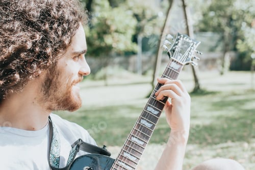 Preview: Attractive man with long hair playing acoustic guitar outdoors, hippie, relax, park lifestyle