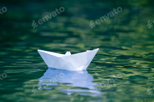 Preview: Close-up of simple small white origami paper boat floating quietly in blue clear river