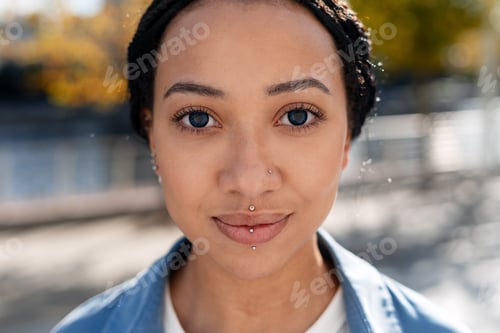 Preview: Portrait of beautiful woman with braids and facial piercings posing outdoors looking at camera