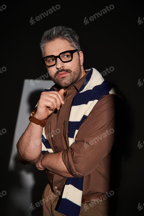 Preview: Stylish man in glasses poses elegantly in a modern studio setting