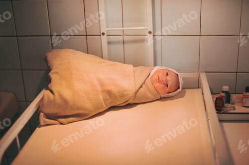 Preview: A newborn baby wrapped up after birth lies on the table