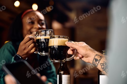 Preview: Close up of couple toasting with beer in a pub.