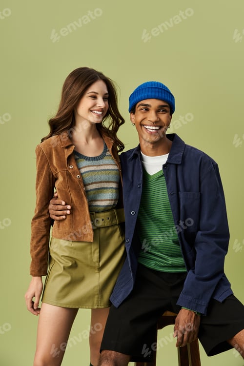 Preview: A stylish young couple wearing vibrant autumn outfits against a soft green backdrop