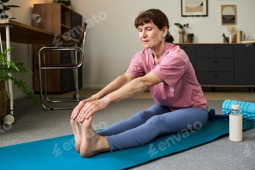 Preview: Senior Caucasian Woman Practicing Seated Forward Bend Stretch Indoors
