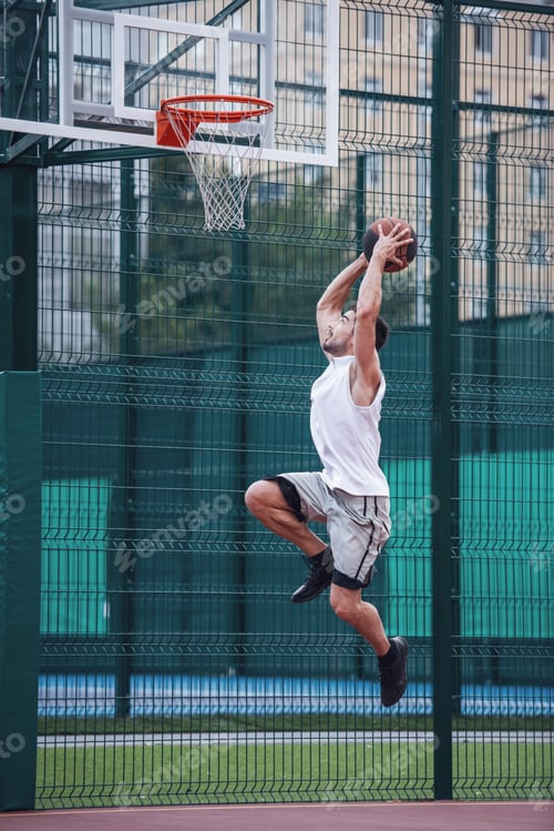 Preview: Focused Man Playing Basketball Outside in Daytime