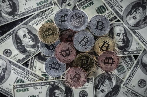 Preview: top view of pile of various bitcoins on dollar banknotes