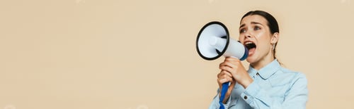 Preview: brunette woman in denim shirt screaming in loudspeaker isolated on beige, panoramic shot
