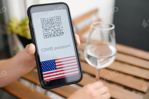 Preview: Woman demonstrates Covid pass application or digital health passport with QR code and USA flag in