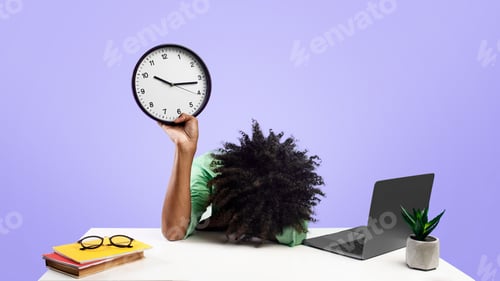 Preview: Tired black male student lying at desk with pc laptop and books, holding clock and putting head on