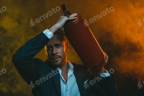 Preview: frightened caucasian man in suit holding fire extinguisher