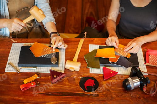 Preview: High angle view of two women sitting at a table, working in a leather shop.