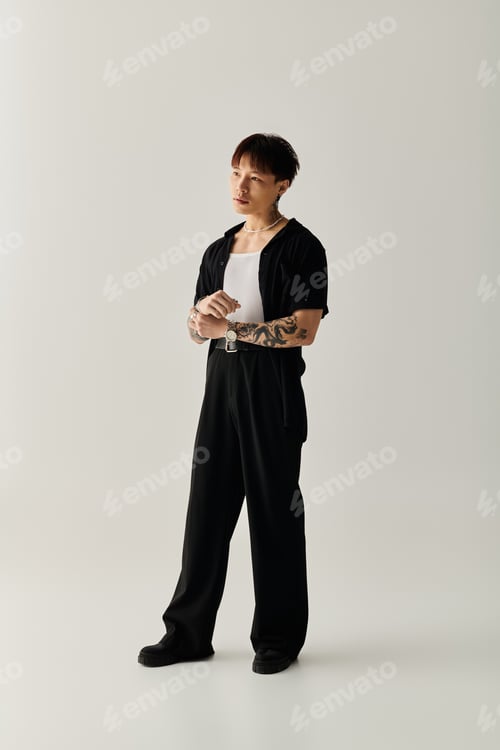 Preview: Stylish Asian man poses confidently in sleek black outfit against simple backdrop