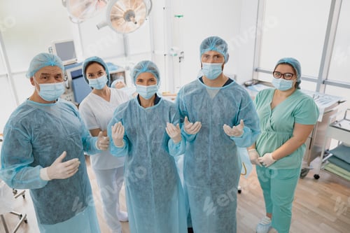 Preview: Team of surgeons in the operating room ready for surgery in clinic looking at camera