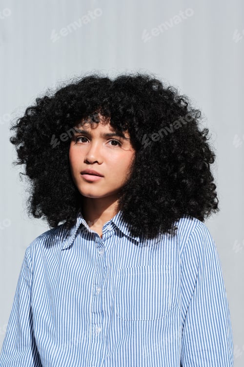 Preview: headshot portrait of Young woman with curly hair looking thoughtful