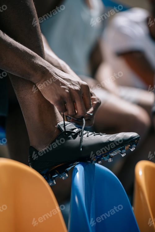Preview: cropped shot of man tying shoelaces while sitting on stadium