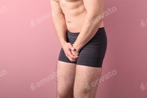 Preview: Young man with urological problems suffering from pain on color background