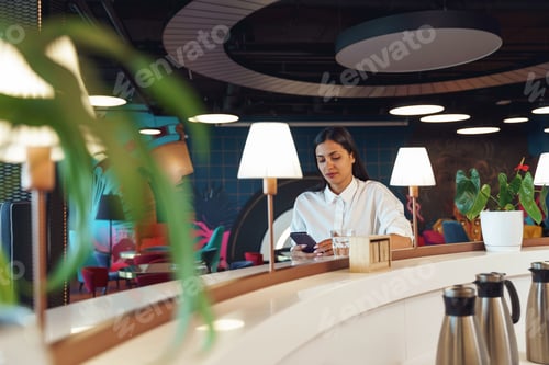Preview: Attractive business woman looking on phone while resting in office during break time