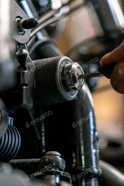 Preview: motorcycle workshop Biker mechanic in garage putting key into power box to start motorcycle close up