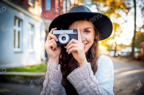 Preview: Beautiful stylish woman on city street at sunny day holding vintage retro camera