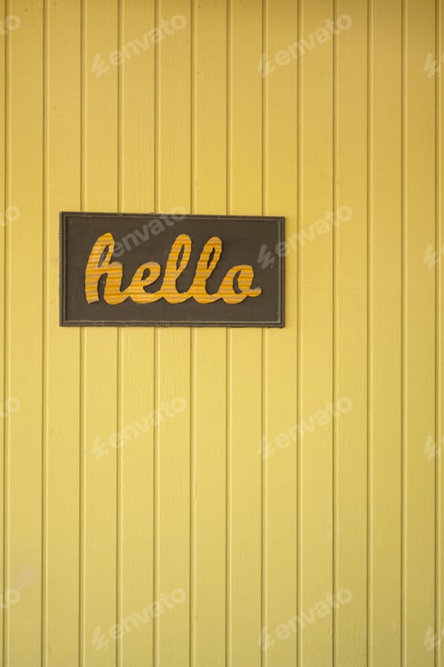Preview: Vibrant yellow beadboard wall with a cheerful hello greeting sign displayed prominently