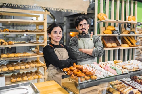 Preview: Bakers smiling with arms crossed in front of pastry display case