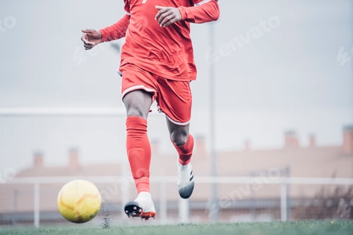 Preview: African soccer player with red outfit playing soccer.