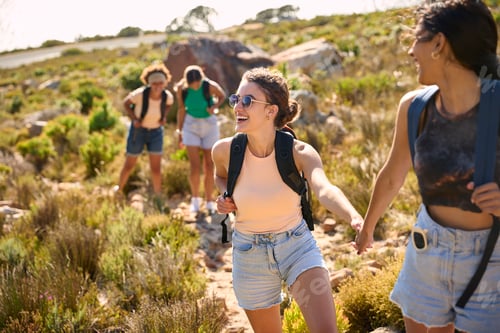 Preview: Group Of Female Friends With Backpacks Helping Each Other On Hike In Countryside On Coastal Path