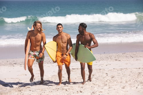 Preview: Front view of diverse male friends walking with surfboard on the beach