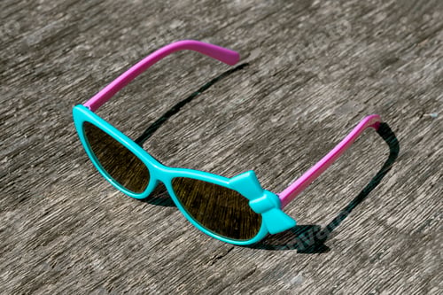 Preview: Blue sunglasses with pink arches on gray background.