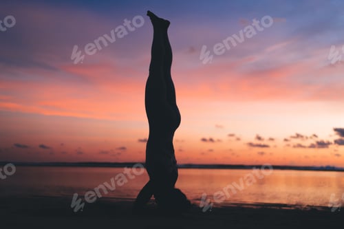 Preview: Strong female with athletic body standing on hands and head in asana stretching muscles