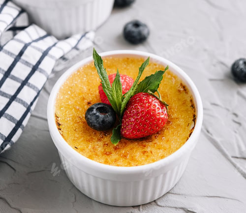 Preview: cup of creme brulee with dessert plug and mint leave with berries