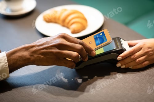 Preview: African american businessman paying with cellphone at cafe