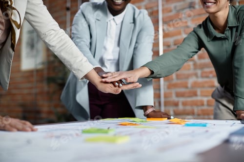 Preview: Close-up of businesswomen gathering hands in unity while working on new project in the office.